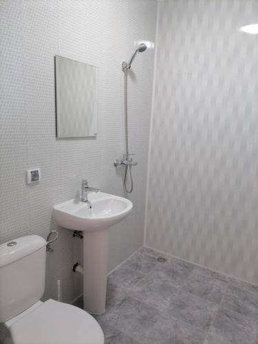 a white bathroom with a toilet and a sink at Къща за гости Релиса in Razgrad