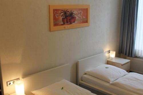 a bedroom with two beds and a picture on the wall at Hotel Weidenhof in Düsseldorf