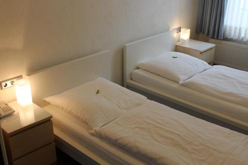 a bedroom with a bed and two night stands with lights at Hotel Weidenhof in Düsseldorf