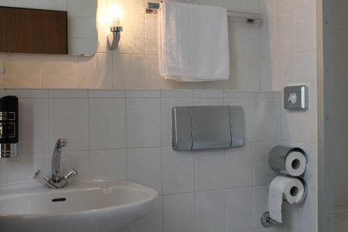 a bathroom with a sink and a toilet paper dispenser at Hotel Weidenhof in Düsseldorf