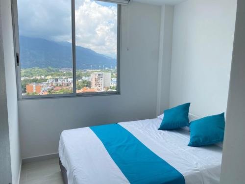 a bed with blue pillows in a room with a window at Nuevo Apartamento Moderno con Excelente Ubicación in Ibagué
