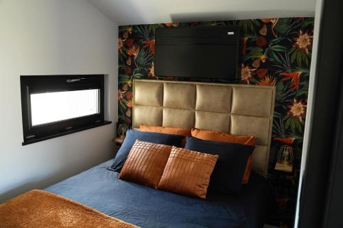 a bedroom with a bed with a flat screen tv above it at B&B het duinhuisje met jacuzzi, gratis parkeren, 2 fietsen te leen, airco in Zandvoort