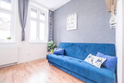 a living room with a blue couch in a room at Seredyńskiego Gdańsk Studio Apartment in Gdańsk