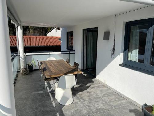 a patio with a wooden table and chairs on a balcony at Gemütliche Wohnung mit großer Terrasse in Bruckmühl