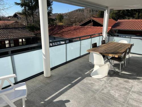 a patio with a wooden table and chairs on a roof at Gemütliche Wohnung mit großer Terrasse in Bruckmühl