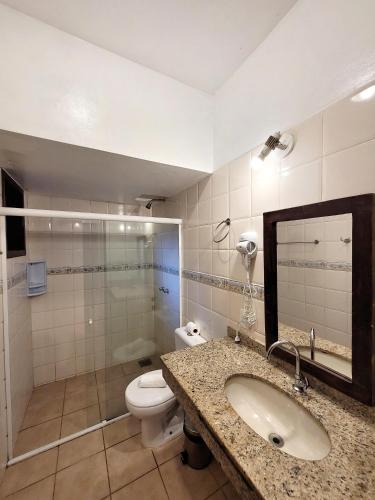 a bathroom with a sink and a toilet and a mirror at Pousada Centro Class in Búzios