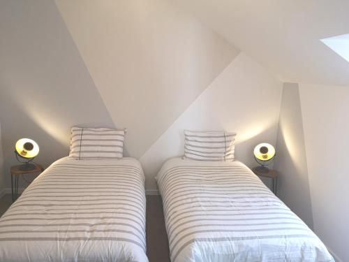 two beds in a room with white walls and lights at Cottage AU TERMINUS 3 climatisé in Hautvillers