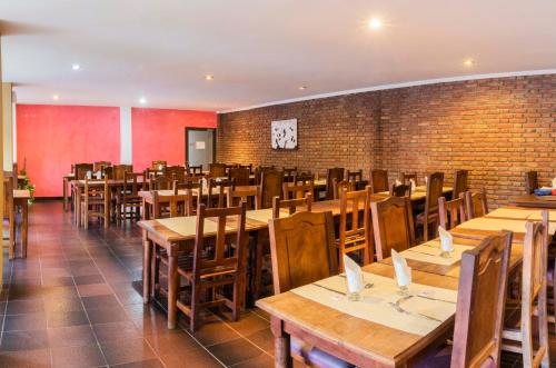 a restaurant with wooden tables and chairs and a brick wall at Hotel Valle Del Sol in Merlo