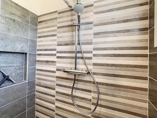 a shower in a bathroom with a striped wall at Galets Blancs Yourhosthelper in Royan