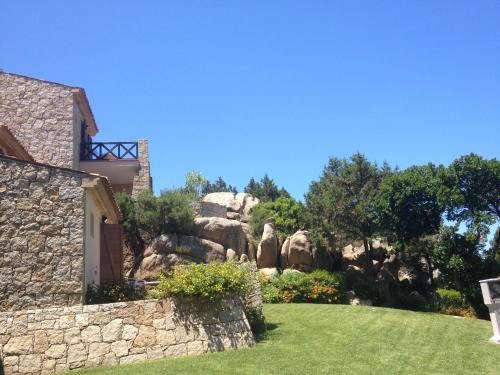 ein Haus mit einer Steinmauer und einem Hof in der Unterkunft RESIDENCE PORTO PICCOLO - appartamento D8 in Baja Sardinia