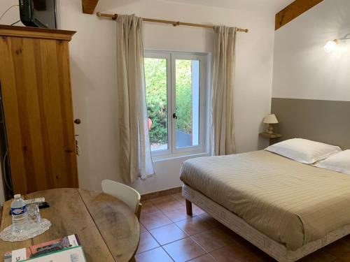 een slaapkamer met een bed, een tafel en een raam bij Gîte L'Olivier (Bastide Sainte Agnès) in Carpentras