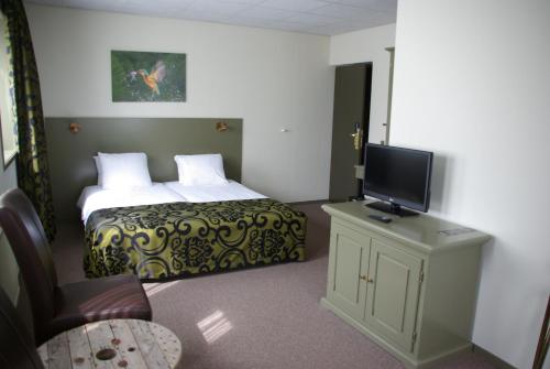 a hotel room with a bed and a flat screen tv at Hotel Sportsbar & Brasserie Dorhout Mees in Biddinghuizen