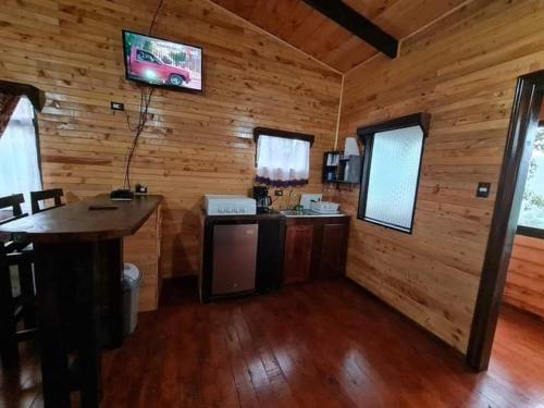 a kitchen in a wooden cabin with a tv on the wall at Las Bromelias Lodge in Paso Macho
