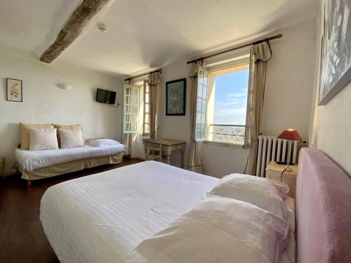 a bedroom with two beds and a desk and a window at Logis Hôtel La Bellaudière in Grasse