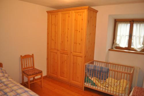 a bedroom with a crib and a wooden cabinet at La Casa di Nicky - San Vito di Cadore in San Vito di Cadore