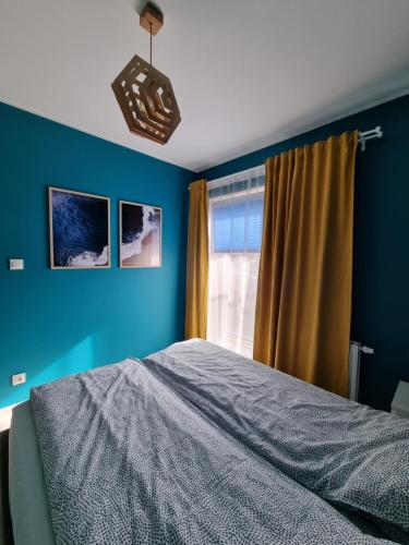 a blue bedroom with a bed and a window at Apartament Sosnowy Las in Gdańsk