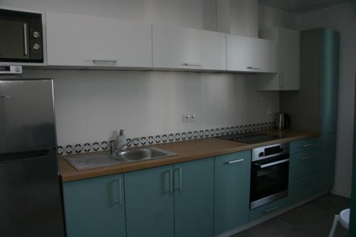 a kitchen with blue cabinets and a sink at Apartament zielony in Konin