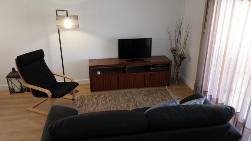 a living room with a couch and a chair and a television at Vila Atlantida Apartment in Vilamoura