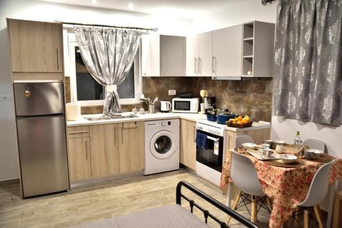 a kitchen with white appliances and a table with chairs at PLUMERIA HOUSE in Archangelos