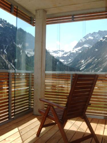 a rocking chair on a balcony with a view of mountains at Ferienwohnungen am Walmendingerhorn in Mittelberg