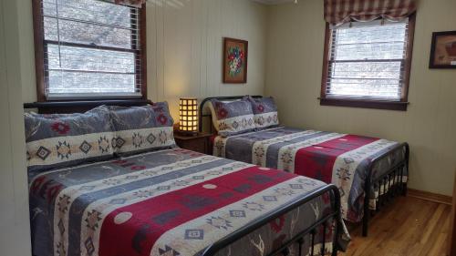 a bedroom with two beds and two windows at Cozy Creek Cottages in Maggie Valley
