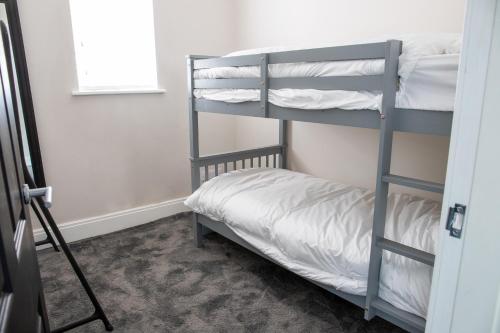 a bedroom with a bunk bed with white sheets at Withnell Stays - Apartment One - Ground Floor in Blackpool