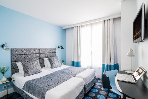 a bedroom with a bed and a desk with a laptop at Hotel Astoria - Astotel in Paris