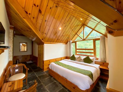 a bedroom with a large bed in a room with wooden ceilings at Nature Bliss - Mount Serene in Manāli