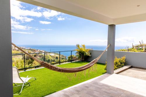 a hammock on a balcony with a view of the ocean at House - sleeps 3 free parking garden & jacuzzi in Estreito da Calheta