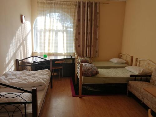 a bedroom with two beds and a window and a table at Freedom in Uzhhorod