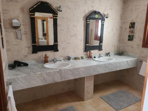 a bathroom with two sinks and two mirrors at Villa Harmony in Charco del Palo