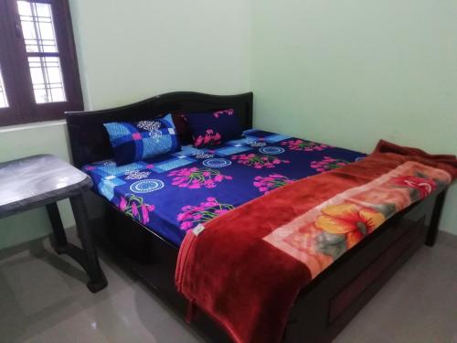 a bed with a blue comforter with flowers on it at Madhuvan Home stay in Rishīkesh