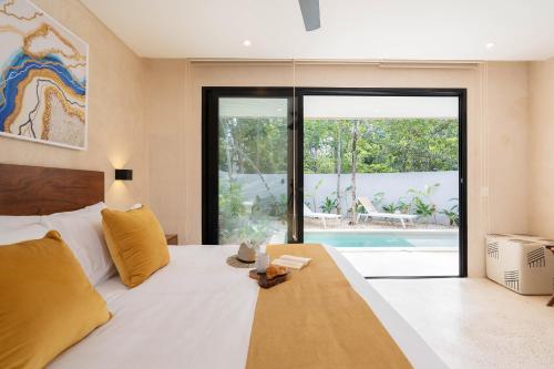 a bedroom with a bed and a swimming pool at Suites at TreeTops Tulum in Tulum