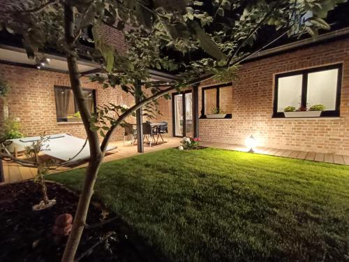 um jardim à noite com um relvado e uma casa em L'Entracte et son spa privatif em Esquelbecq