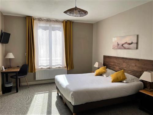 a hotel room with a bed and a desk and window at Le Vauban in Merville-Franceville-Plage