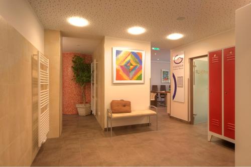 a hospital hallway with a chair and a painting on the wall at Parkhotel Neubauer in Sauerbrunn