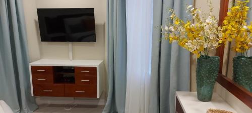 a living room with a television and a vase of flowers at Almond Grove at Sand Castle in Ocho Rios