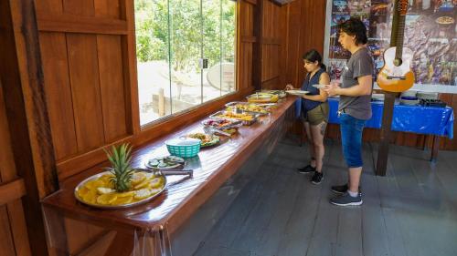 two people standing at a buffet line with food at Amazon Boto Lodge Hotel in Careiro