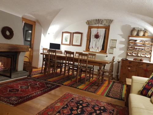 een eetkamer met een tafel en stoelen en een open haard bij Ronchet Baita Vanoi Trentino in Ronco