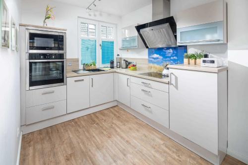 a white kitchen with white cabinets and appliances at Utspann in Norderney