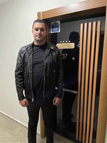 a man in a leather jacket standing in front of a door at Apartman Jaman - Novi Pazar in Novi Pazar