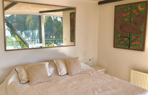 a bedroom with a bed with two pillows and a window at Lofts - Casa El Pangue, Zapallar in Zapallar