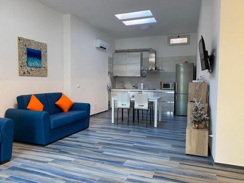 a living room with a blue couch and a kitchen at Appartamenti Acquazzurra in Portoferraio