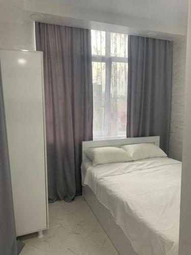 a bedroom with a white bed and a window at Kakha's Apartment in Batumi
