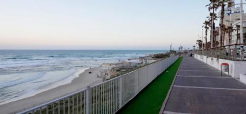 a walkway to the beach with the ocean and buildings at Hotel Apartment TLV-bat yam 81 in Bat Yam