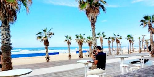a man taking a picture of a beach with palm trees at Hotel Apartment TLV-bat yam 81 in Bat Yam