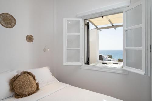 a bedroom with a bed and a window with the ocean at Red Beach Harmony suites Modestos in Akrotiri