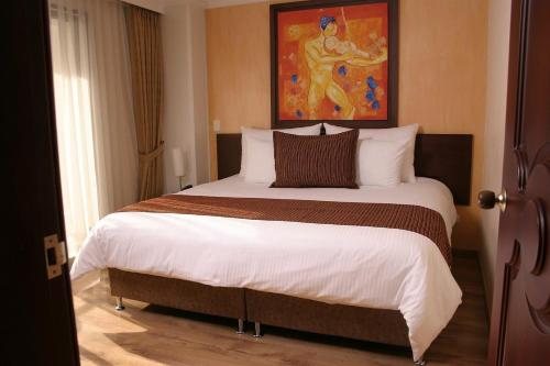 a bedroom with a large bed with a painting on the wall at Hotel Luxor Pereira in Pereira