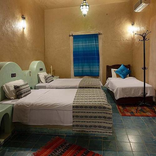 a bedroom with two beds and a window at Riad Dar Ouzine in Merzouga
