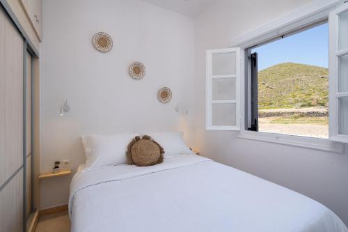 a white bedroom with a bed and a window at Red Beach Harmony suites Sotiria in Akrotiri